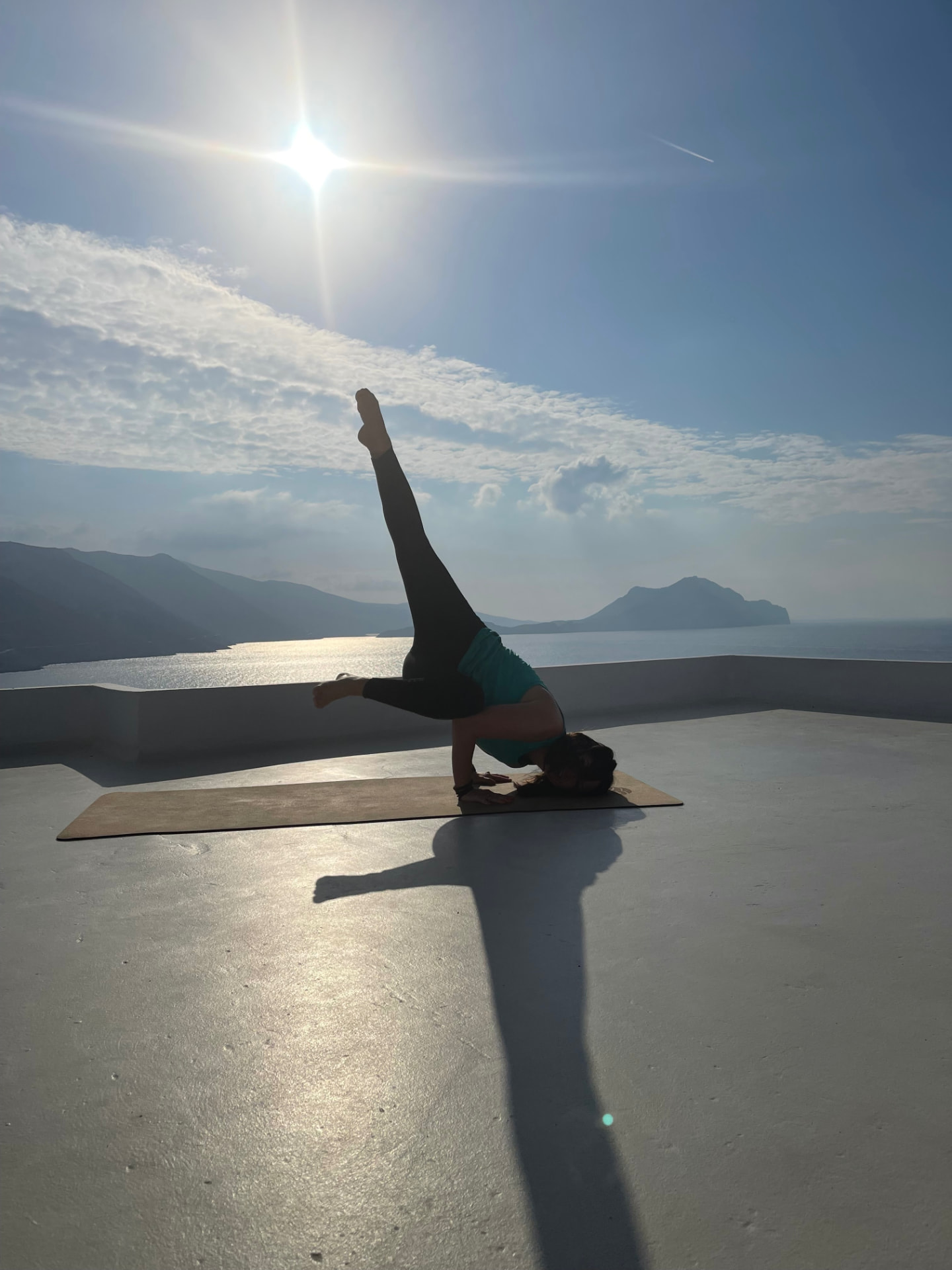 Tara Allen practicing yoga on a terrace overlooking the sea at sunrise