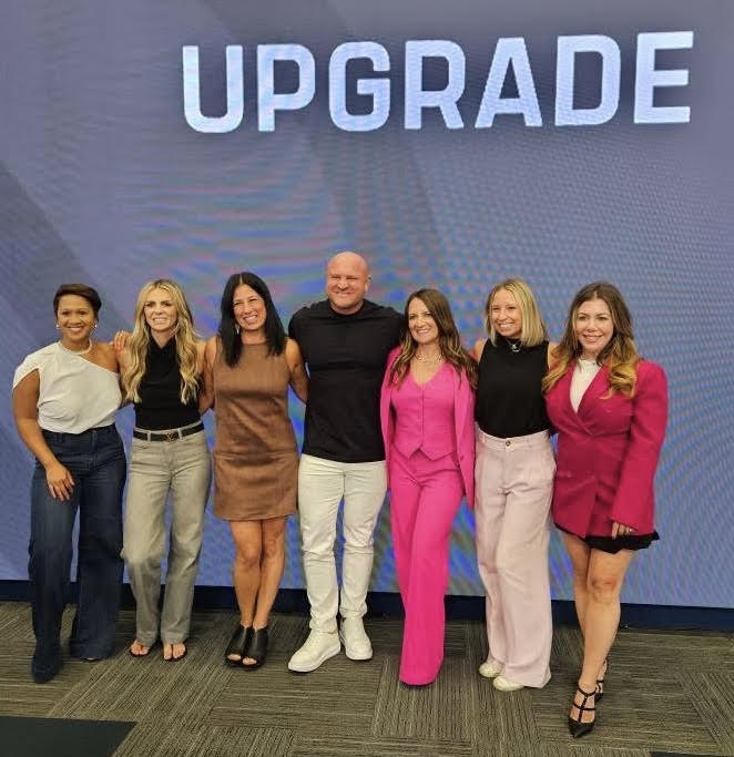 Tara Allen with the Upgrade Community leadership team under the UPGRADE sign