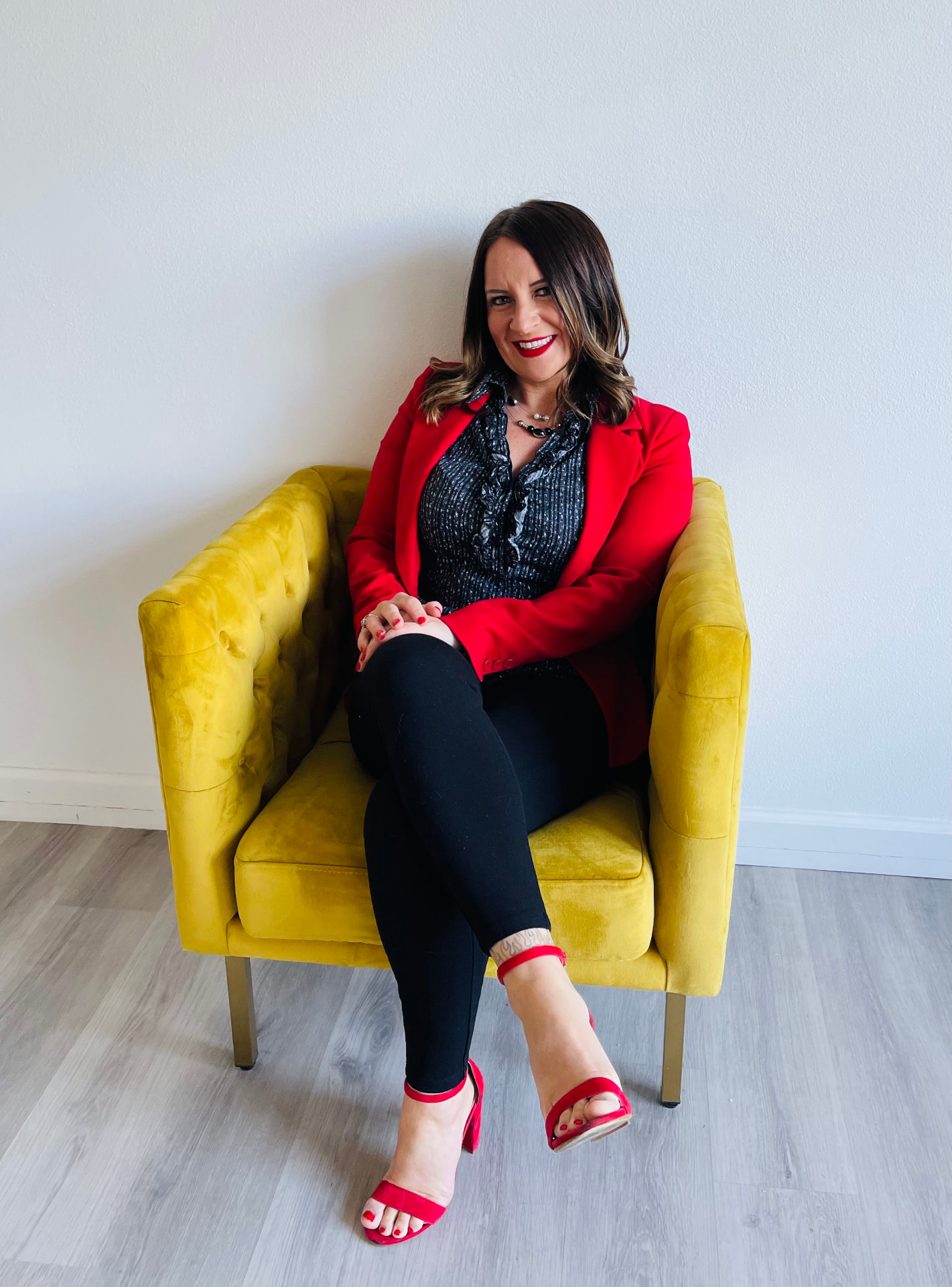 Tara Allen in a red blazer seated on a yellow chair